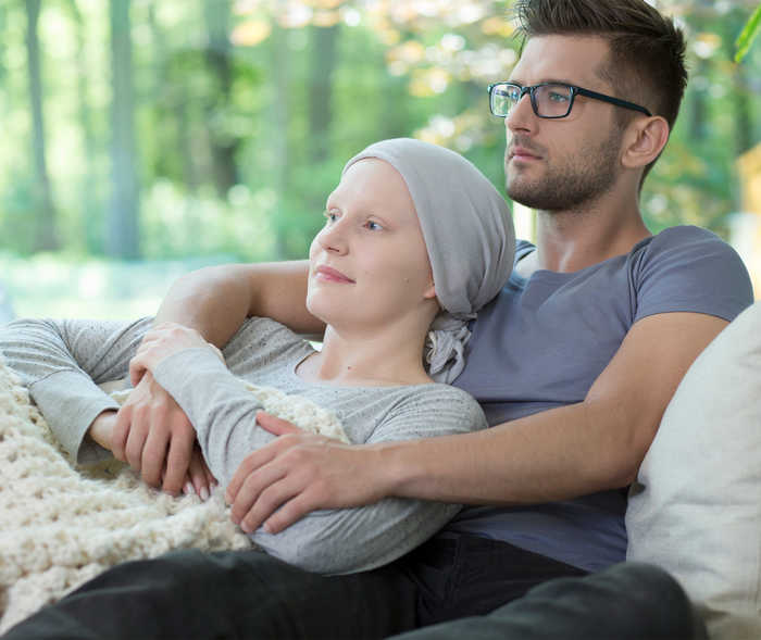 Teaser Chemotherapie Ein Mann hält eine Frau im Arm. beide sitzen auf einer Bank.