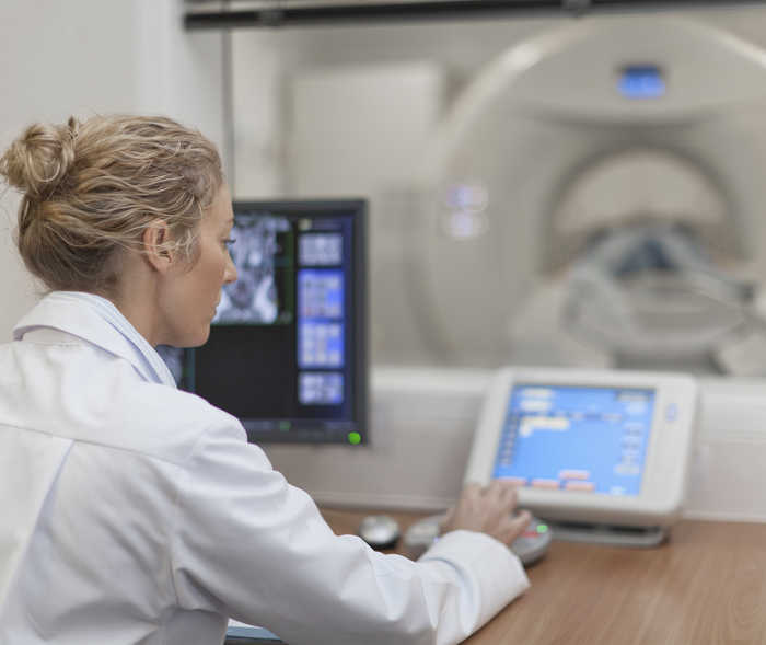 Une collaboratrice d’une équipe de radiologie utilise un appareil IRM.