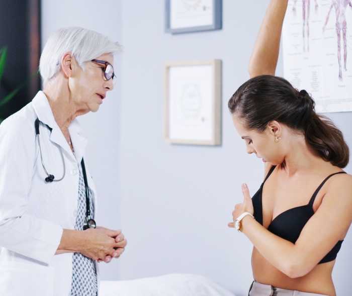 Une médecin examine l’aisselle d’une patiente.