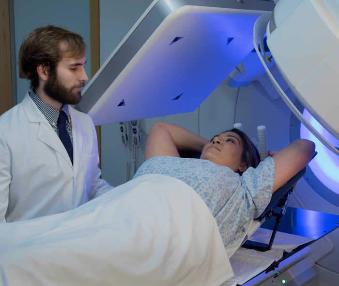 Femme sous un appareil de radiothérapie.