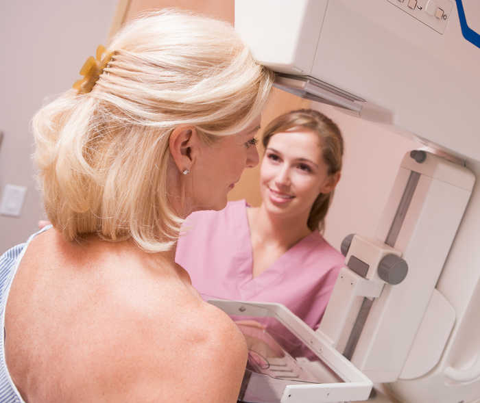 Une technicienne en radiologie réalise une mammographie sur une femme âgée.