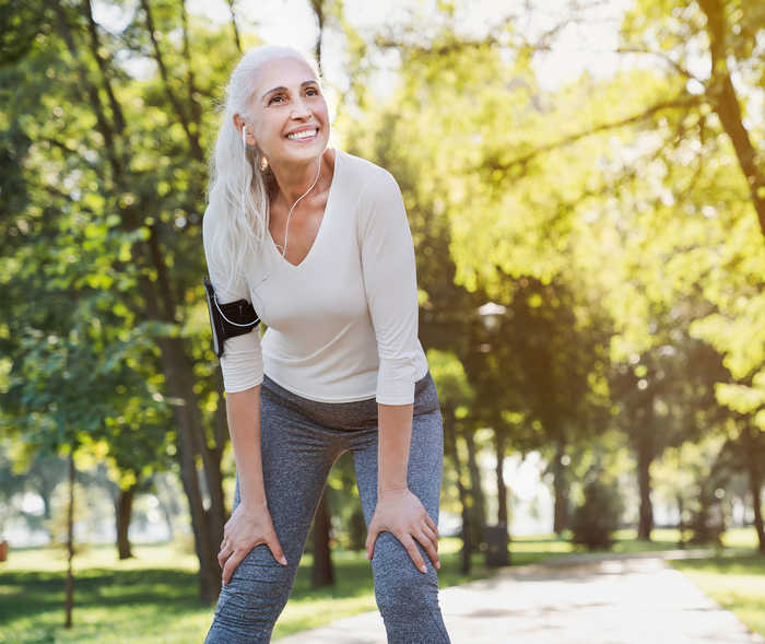 Une femme en tenue de sport appuie ses mains sur ses cuisses.