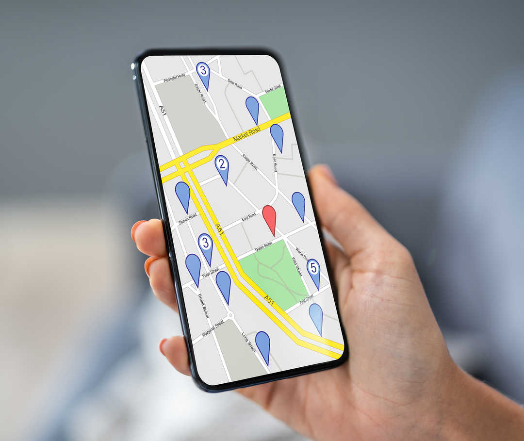Nahaufnahme einer Hand mit einem Smartphone, auf dem ein Kartenausschnitt zu sehen ist.