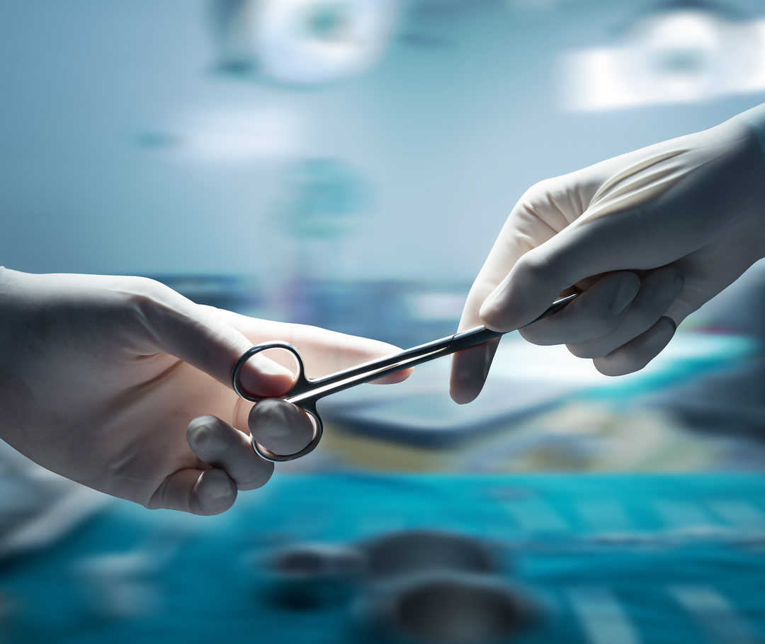 Gros plan sur deux mains gantées qui tiennent des ciseaux.