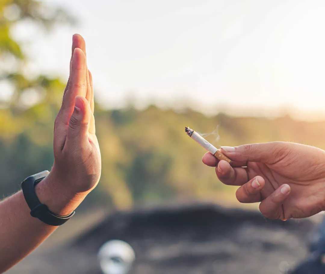 Primo piano di due mani, una con il palmo sollevato e l’altra che tiene una sigaretta. 