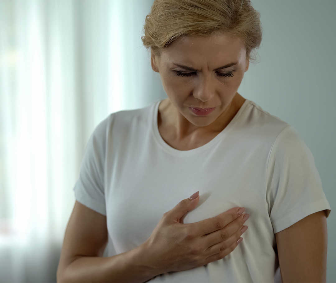 Antihormontherapie vor den Wechseljahren Eine Frau legt sich eine Hand auf die Brust.