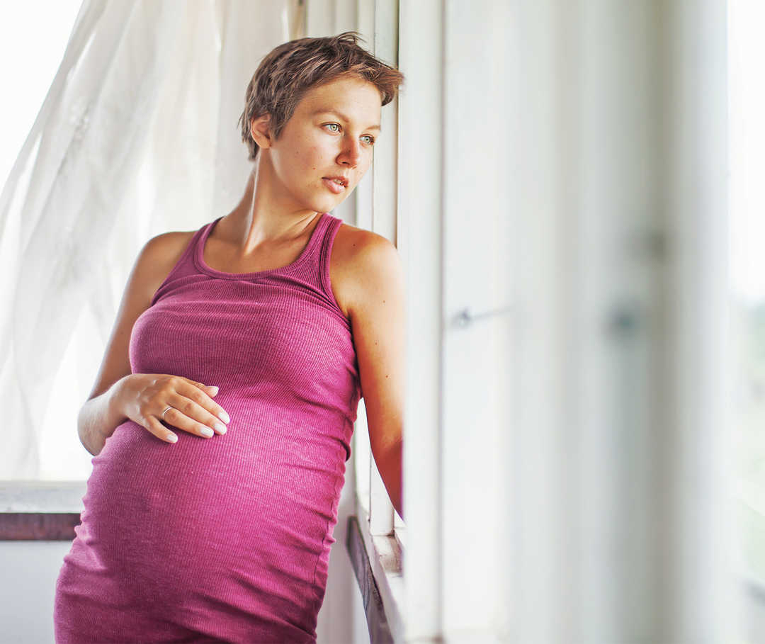 Eine schwangere Frau streicht sich über den Bauch.