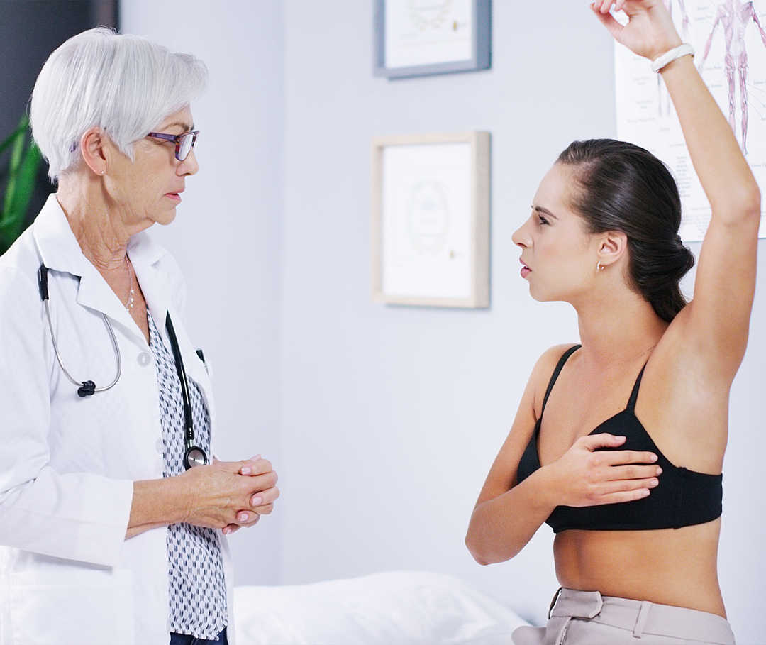 Links eine Frau in weissem Kittel, daneben eine Frau im BH, die einen Arm nach oben streckt.