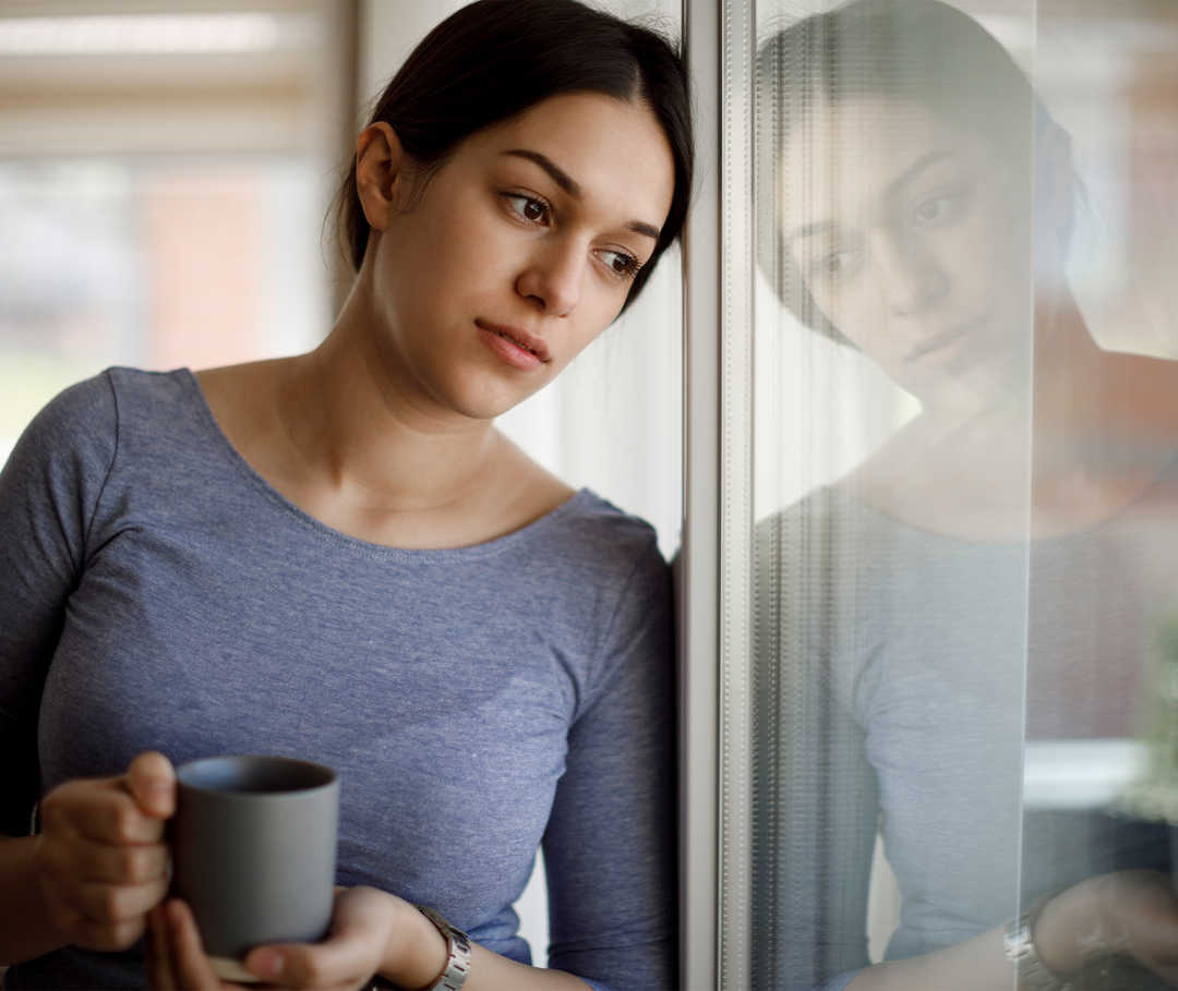 Une femme tient une tasse dans sa main.