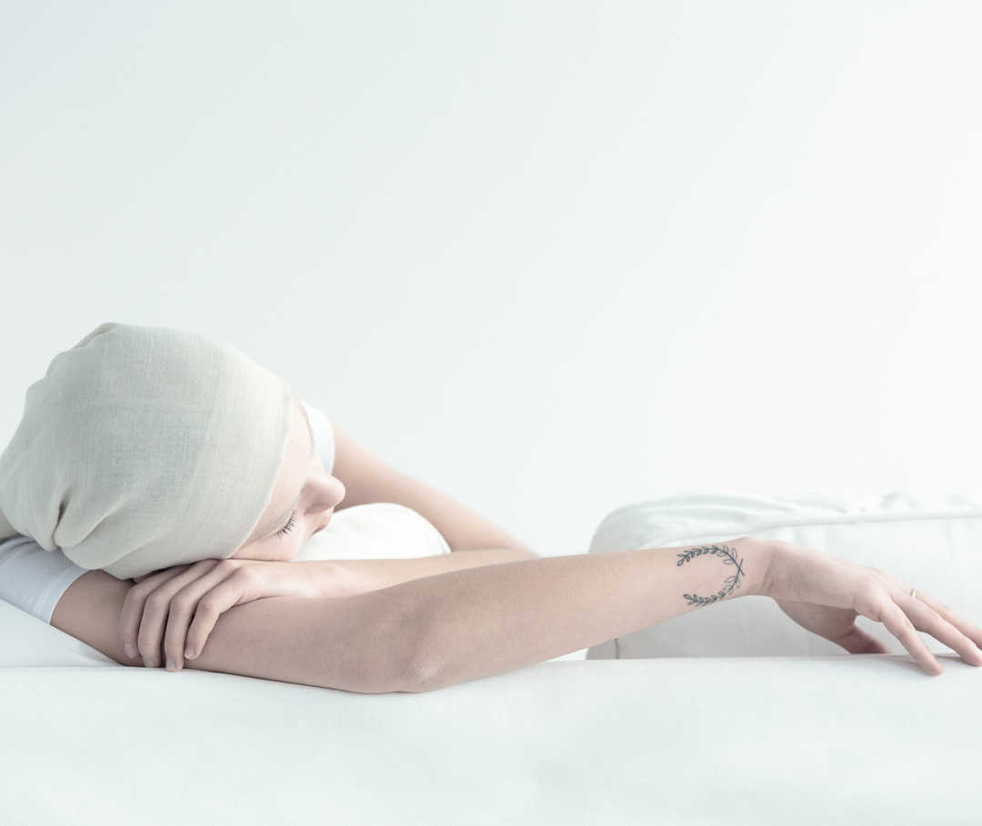 Une femme est allongée sur le côté, la tête recouverte d’un foulard.